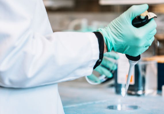A researcher in the lab with a syringe.