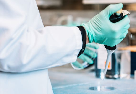 A researcher in the lab with a syringe. 