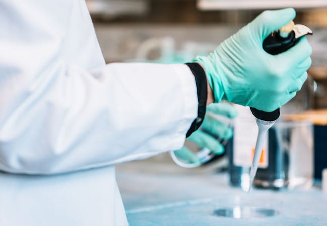 A researcher in the lab with a syringe.