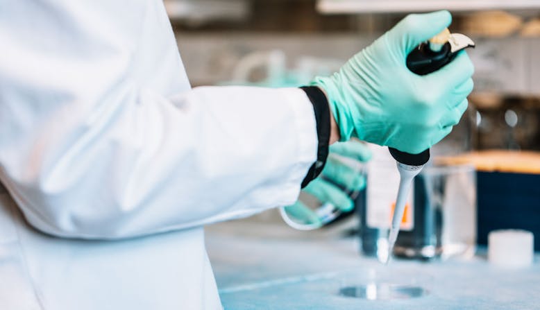 A researcher in the lab with a syringe.