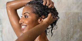 A young woman uses a psoriasis shampoo recommended by NPF.