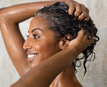 A young woman uses a psoriasis shampoo recommended by NPF.