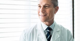 Dermatologist Ronald Prussick smiles while wearing a white coat.