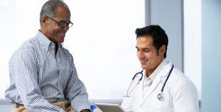 A man sits with his doctor smiling.