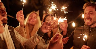 A group of young friends playing with sparklers in the dark.
