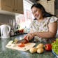 A woman chops fresh vegetables in her kitchen.
