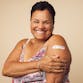 A woman smiles after receiving a vaccination on her arm.