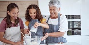 A grandmother, mother, and daughter baking in the kitchen.