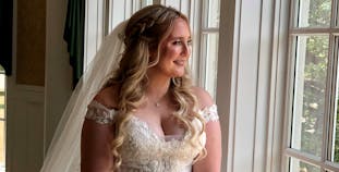 Victoria Ridge in her wedding gown looks out a window.