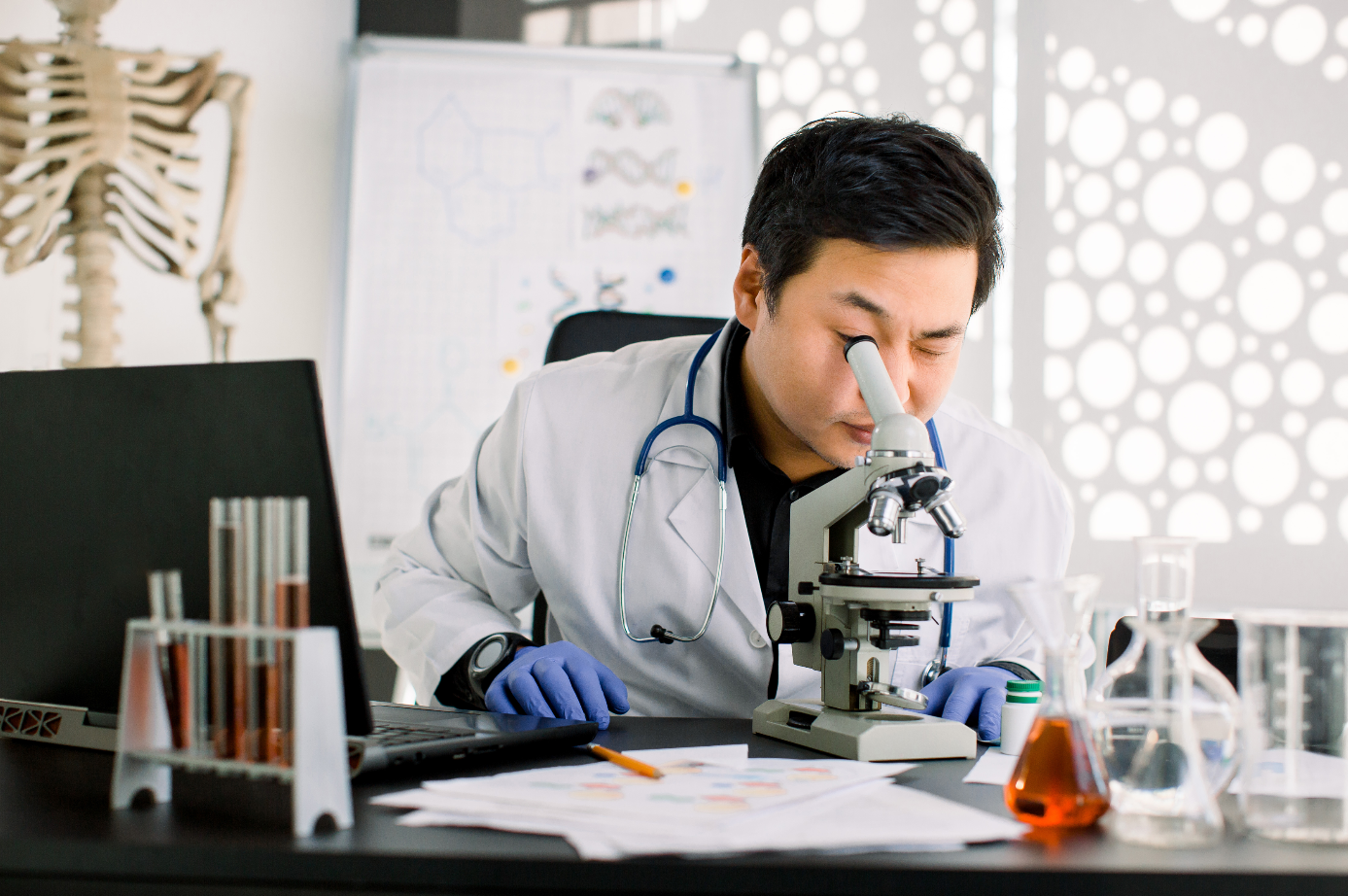 A male researcher looks into a microscope 