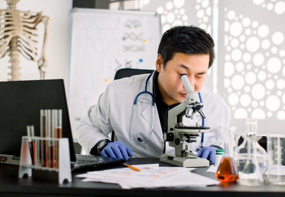 A male researcher looks into a microscope 