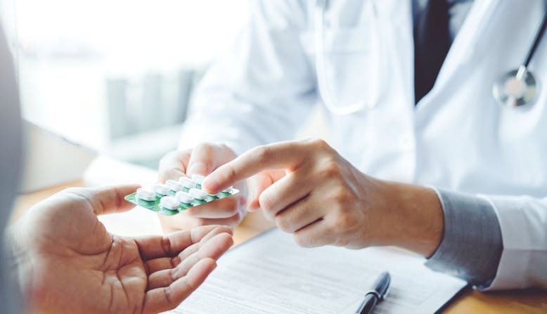 A doctor shows a patient medication in a professional office.