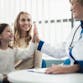 A doctor high-fiving a little girl, while a woman looks on. Everyone is smiling.