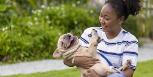 A woman playing with a pug dog.