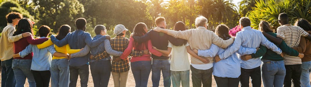 A group of people embrace one another, shown from the back.