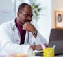A doctor sits in front of a laptop.