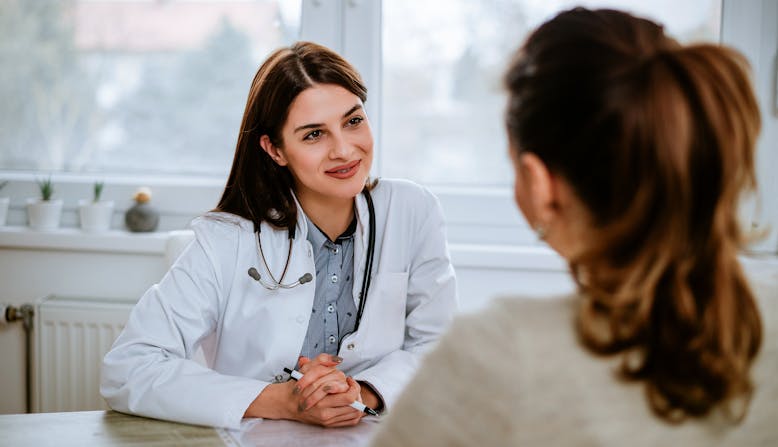 Woman doctor listening to woman patient in an office.