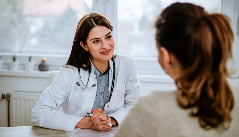 Woman doctor listening to woman patient in an office. 