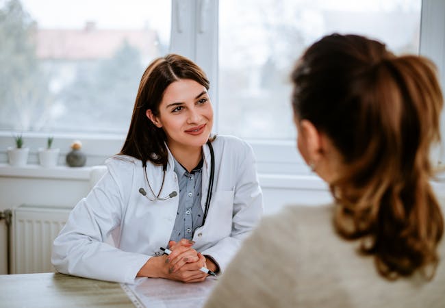 Woman doctor listening to woman patient in an office.