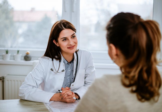 Woman doctor listening to woman patient in an office. 