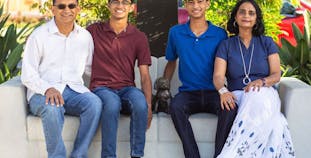 The Kumar family pose outside on a couch.