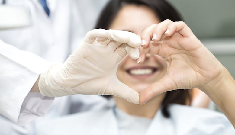 A patient and doctor make a heart shape with their hands in a hospital.