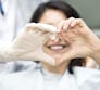 A patient and doctor make a heart shape with their hands in a hospital.