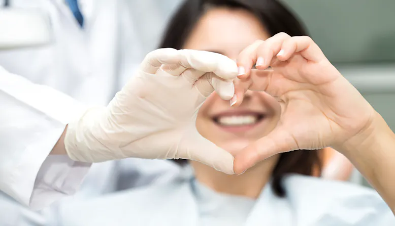 A patient and doctor make a heart shape with their hands in a hospital.