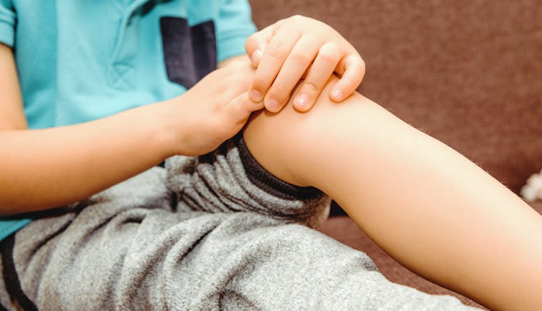 A child holding their knee in pain.