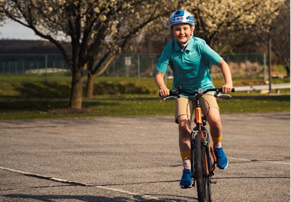A young boy smiles while riding a bike outside. 
