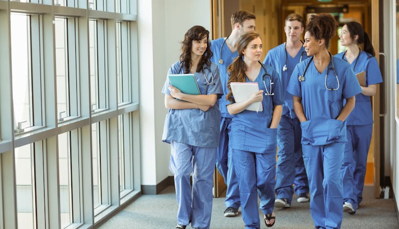 A group of medical professionals walks down a hallway.