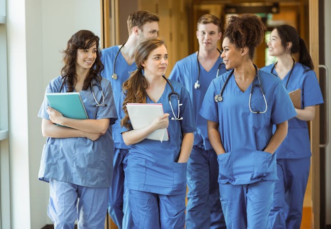 A group of medical students walks down a hallway.