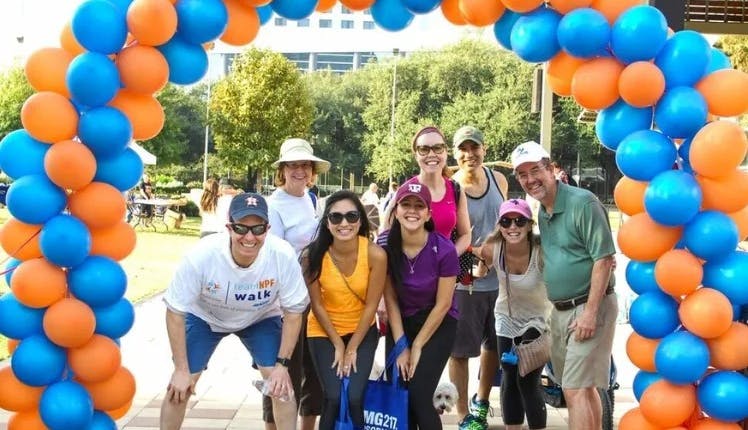 A group of people stand under an NPF balloon arch at an NPF event.