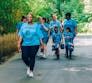 A group of varied aged individuals walk with blue Plaque Busters tshirts.