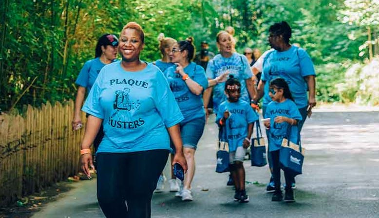 A group of varied aged individuals walk with blue Plaque Busters tshirts.