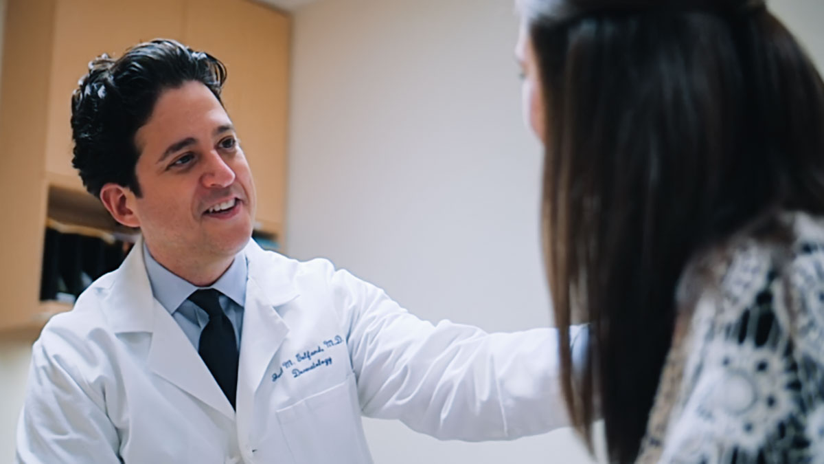 Male doctor talks to a female patient in an exam room. 