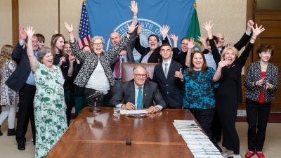 Gov. Inslee signs a bill into law with NPF advocates in the room.