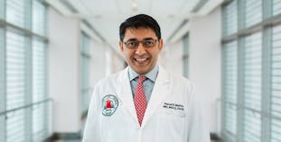 Researcher Nehal Mehta smiles while wearing his white coat.