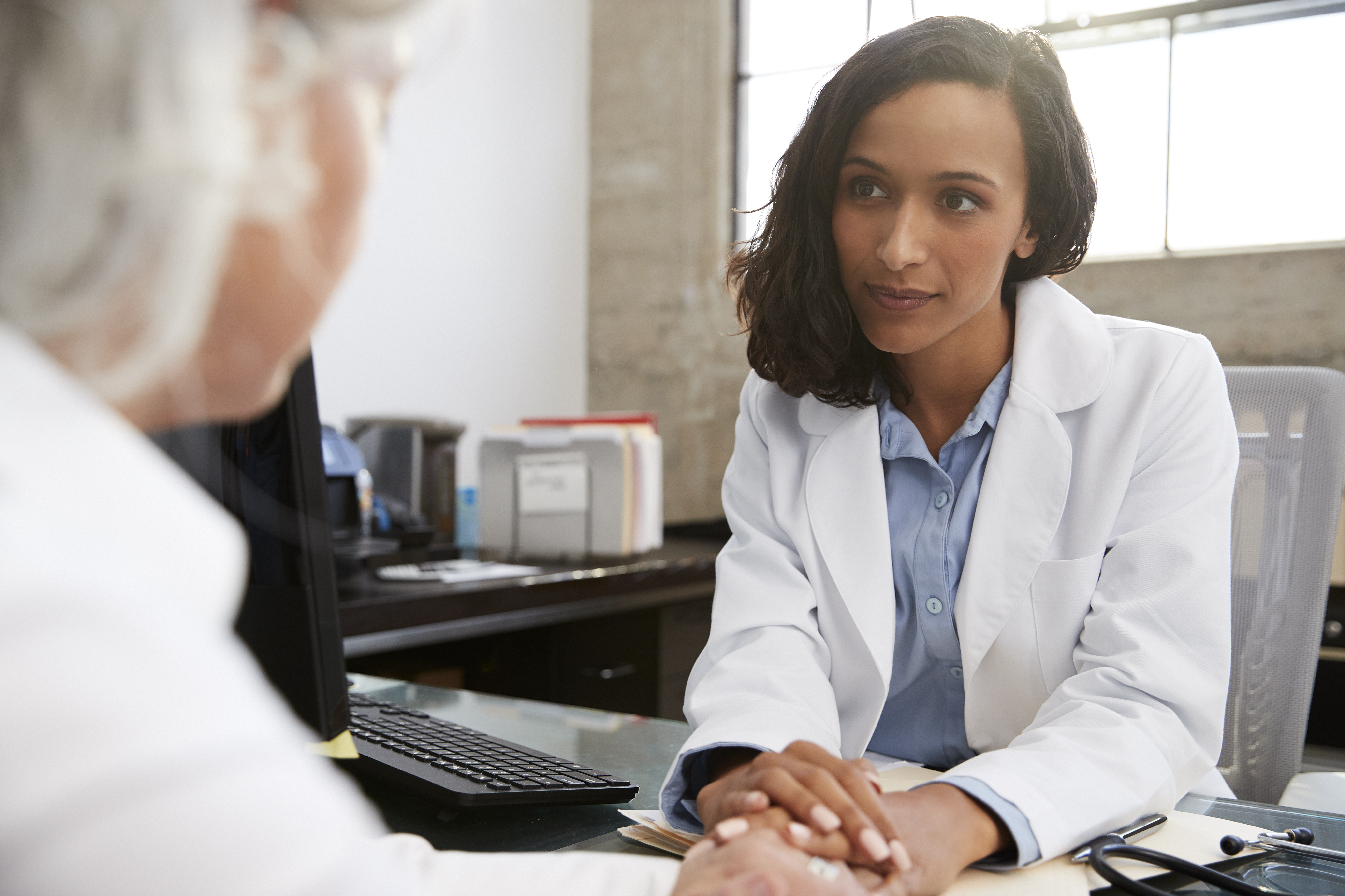 Photo of a healthcare professional consulting with a patient at a desk.