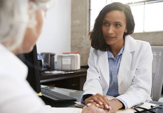 Photo of a healthcare professional consulting with a patient at a desk.