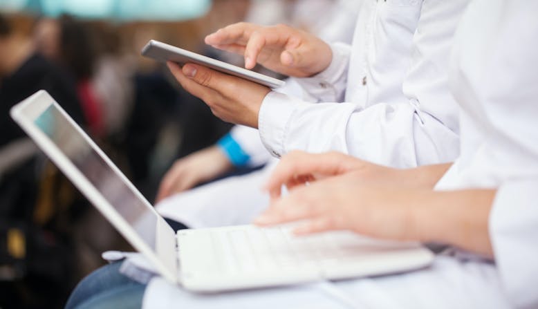 Care providers sitting in a lecture taking notes with their devices