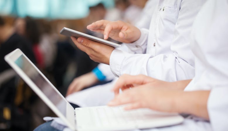 Care providers sitting in a lecture taking notes with their devices