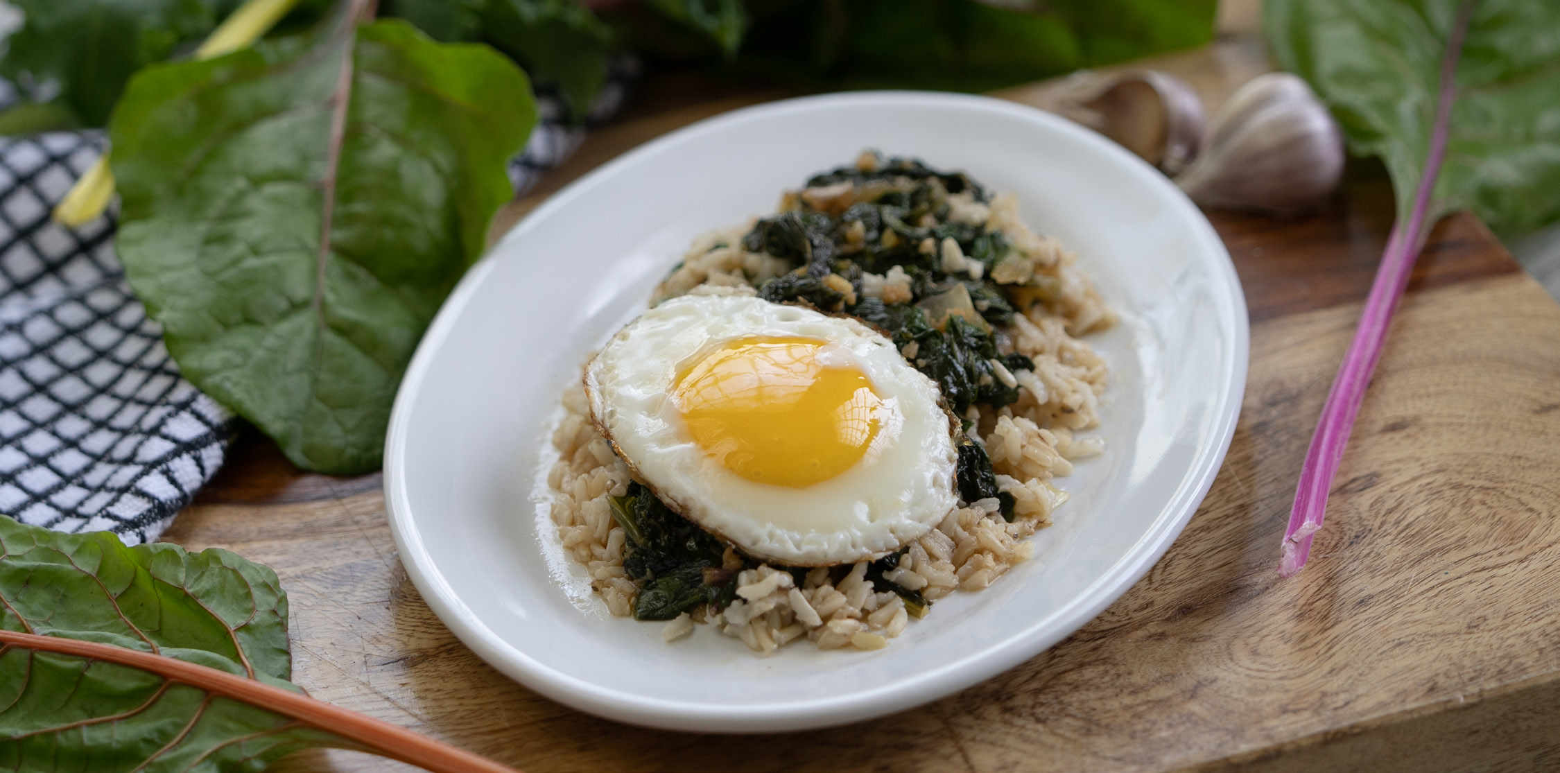 A dish of health grains and greens with a fried egg on top.