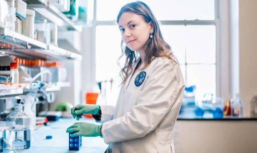 A female researcher in the lab poses and smiles for the camera.