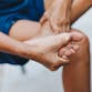 A person holds their foot and massages their arch and ankle.