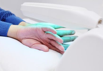A pair of hands placed under a light medical device. 
