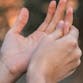 One hand gripping another as if in pain. A graphic for PsA Action Month 2022 overlaid.