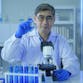 Scientist holding liquid chemical tube in laboratory.