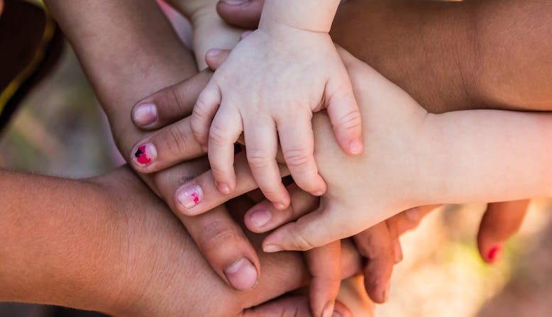 Children and adult hands coming together.