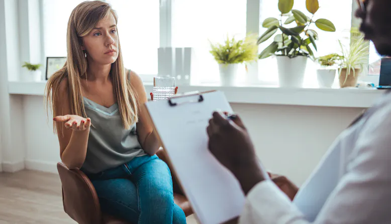 A woman is frustrated with a doctor holding a clipboard.